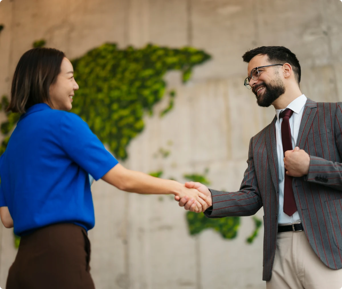 Business meeting handshake with green backdrop.
